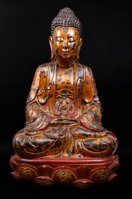 une statue en bois représentant un Bouddha assis sur une table