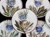 four plates with flowers painted on them on a black surface