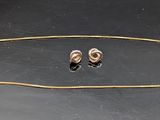 Ensemble collier et boucles d'oreilles plaqués or sur un fond noir