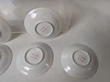 four white porcelain cups and saucers sitting on top of a white table