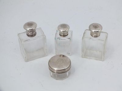 three small glass bottles with silver lids sitting on a white surface