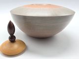a small wooden object sitting next to a large bowl