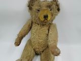 a brown teddy bear that is sitting on a white surface