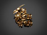 une broche en or ornée de perles et de feuilles sur fond noir