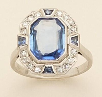 a close up of a ring with a blue stone surrounded by diamonds