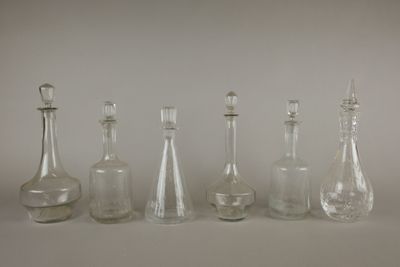 six carafes en verre sont alignées sur une surface blanche