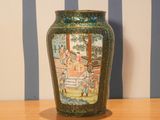 a vase with a painting on it sitting on a table
