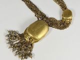 gold plated necklace with chain and tassels on a white surface