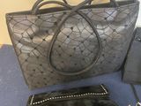 two purses are sitting on a table next to a cell phone