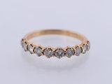 a yellow gold ring with five white diamonds on a white surface