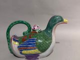 a small teapot with a bird on top of it