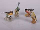trois petites figurines d'oiseaux posées sur une surface blanche