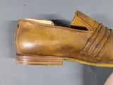 a person holding a pair of brown shoes on a gray surface