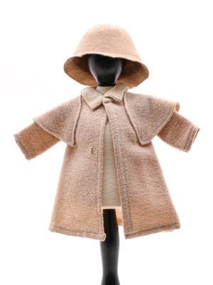 poupée portant un manteau beige à capuche et un nœud papillon
