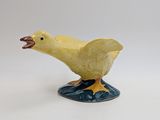 yellow duck figurine on blue base with mouth open