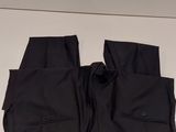 black pants hanging on a clothes rack on a white wall