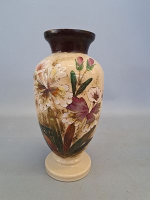 a vase with flowers painted on it sitting on a table