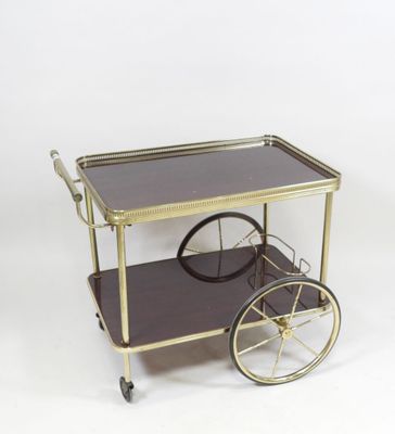 an image of a brass and glass bar cart on wheels