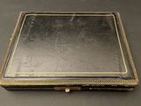 an old black leather box with gold trim and a gold trim around the edges