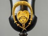 a black vase with a gold decoration on the top of it