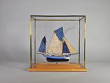 une petite maquette en bois représentant un voilier, exposée dans une vitrine