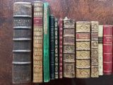 several old books are lined up on a shelf on a table