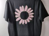 a black shirt with a pink flower on it hanging on a hanger