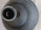 a large metal vase sitting on the floor next to a wall