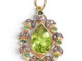 a close up of a pendant with a green stone and green stones