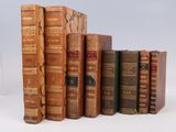 several old books are lined up in a row on a white surface