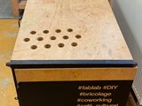 a wooden table with holes on it in the middle of a room
