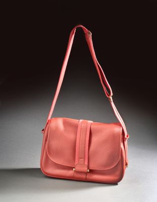 an orange purse sitting on top of a table next to a black wall