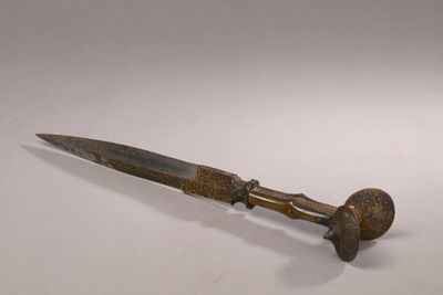 un vieux couteau au manche en bois posé sur une surface blanche
