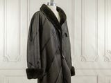 un manteau noir à col de fourrure sur un mannequin
