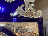 a blue glass clock with a decorative design on the front of it