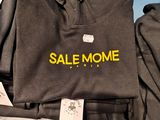 a pile of clothing on a table with a sale mome sign on it