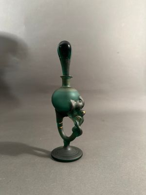 un petit vase vert muni d'une anse noire, posé sur une table