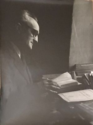 an old black and white photo of a man sitting at a desk with a book