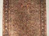 Un tapis persan ancien est accroché à un mur blanc