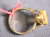 a gold ring with a diamond on it on a gray surface