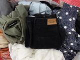 a pile of clothes that is sitting on a bed