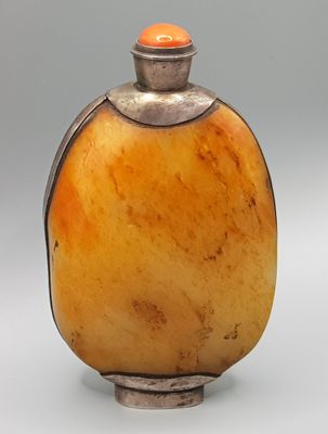 une photo d'une bouteille en verre orange avec un bouchon argenté