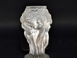un vase en verre orné d'une statue, posé sur un fond noir