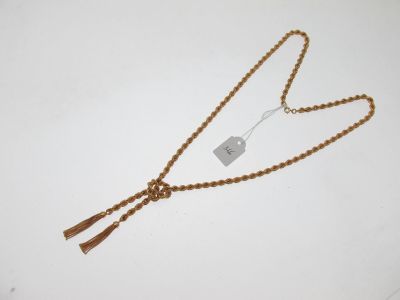 une chaîne en or à laquelle est accrochée une plaque, posée sur une surface blanche
