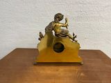 a small statue of a boy sitting on top of a clock