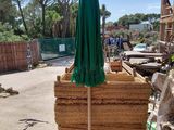 a green umbrella sitting on top of a pile of wood