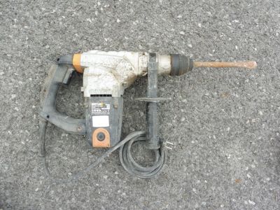 une perceuse posée par terre à côté d'un cordon
