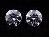 a pair of round brilliant cut diamonds on a black surface