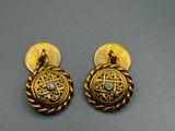 une paire de boucles d'oreilles en or et diamants posées sur une surface grise