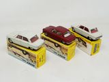 three toy cars sitting on top of boxes on a white surface